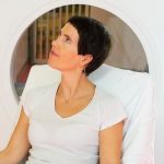 Une femme assise sur une chaise devant un appareil IRM.
